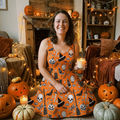 Woman wearing the pumpkin and skull print midi dress in a cozy home